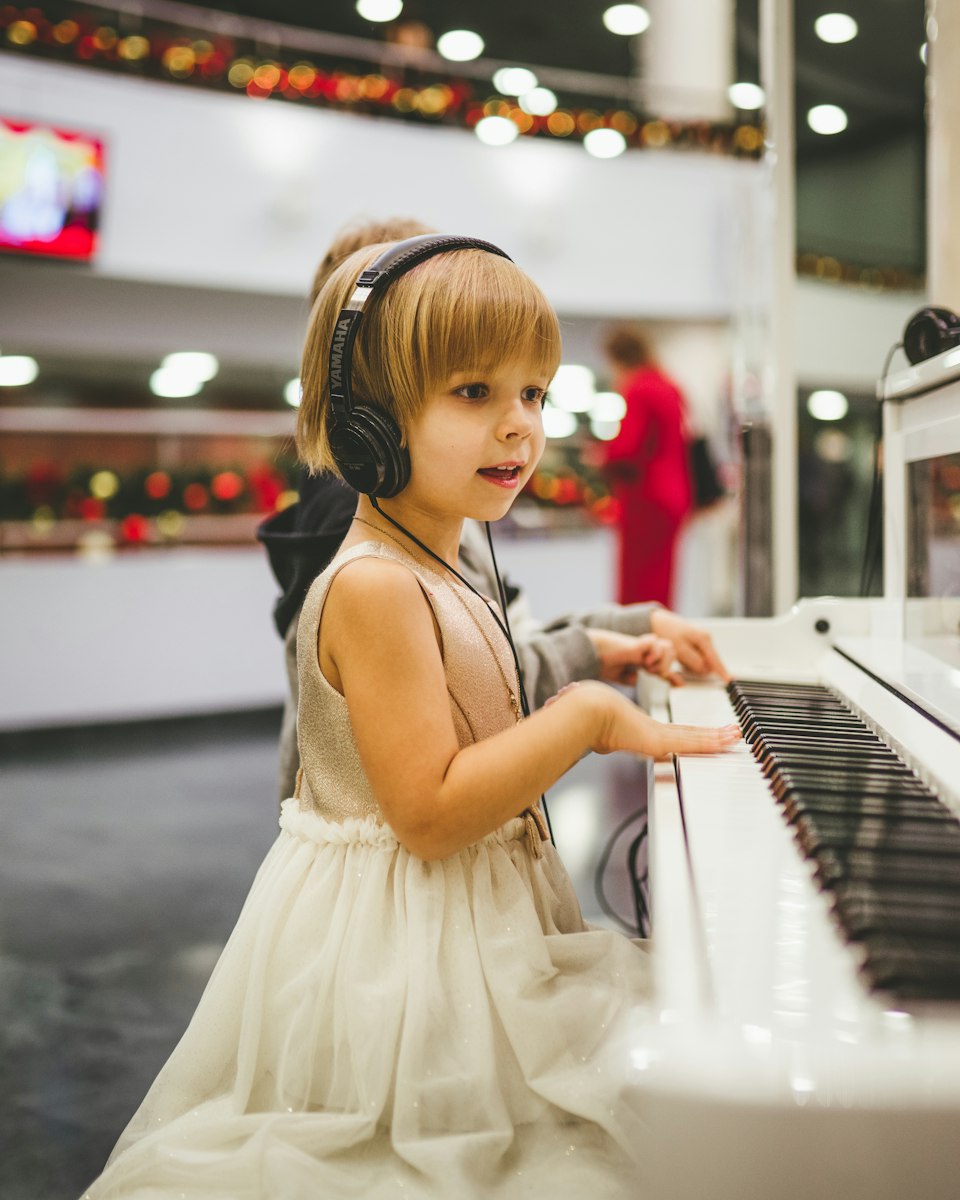 Menina pequena a tocar piano com auscultadores